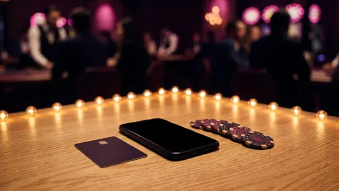 Debit card and smartphone beside casino chips on a light wooden table