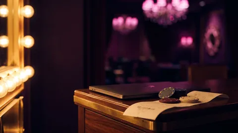 Closed laptop, a few casino chips and a folded blank receipt on a dark wooden desk