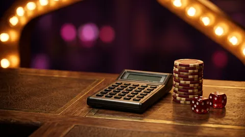 Pocket calculator next to a stack of casino chips and two dice on a walnut desk